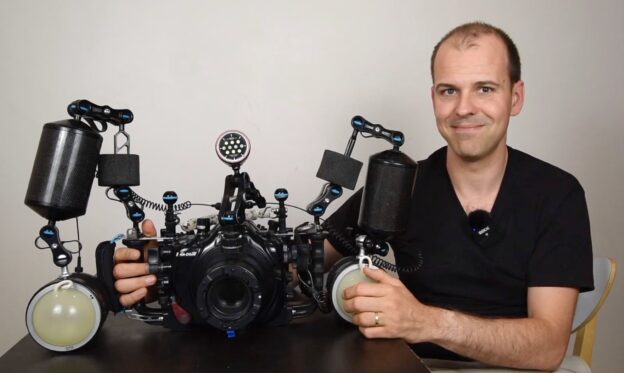 Nicolas REMY holding a nauticam camera housing with two retra flash pro underwater strobes on a table.