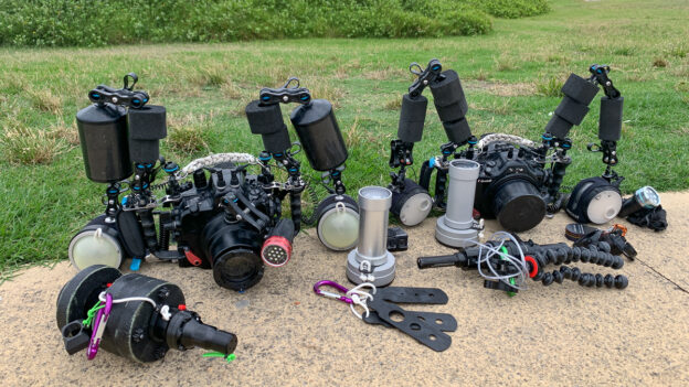 two underwater photography setups laid down on the ground with nauticam camera housings, retra strobes, retra snoots and nauticam EMWL.